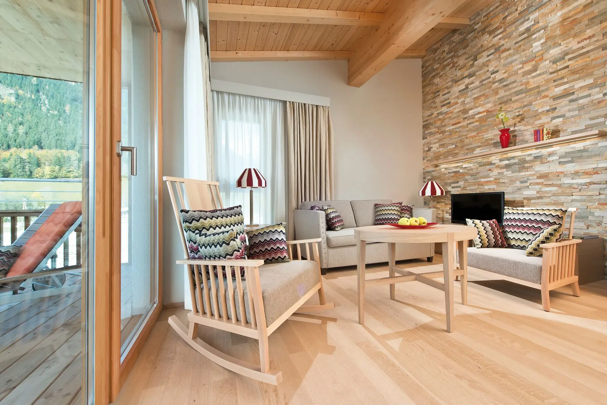 A cozy living room with wooden floor and stone wall.