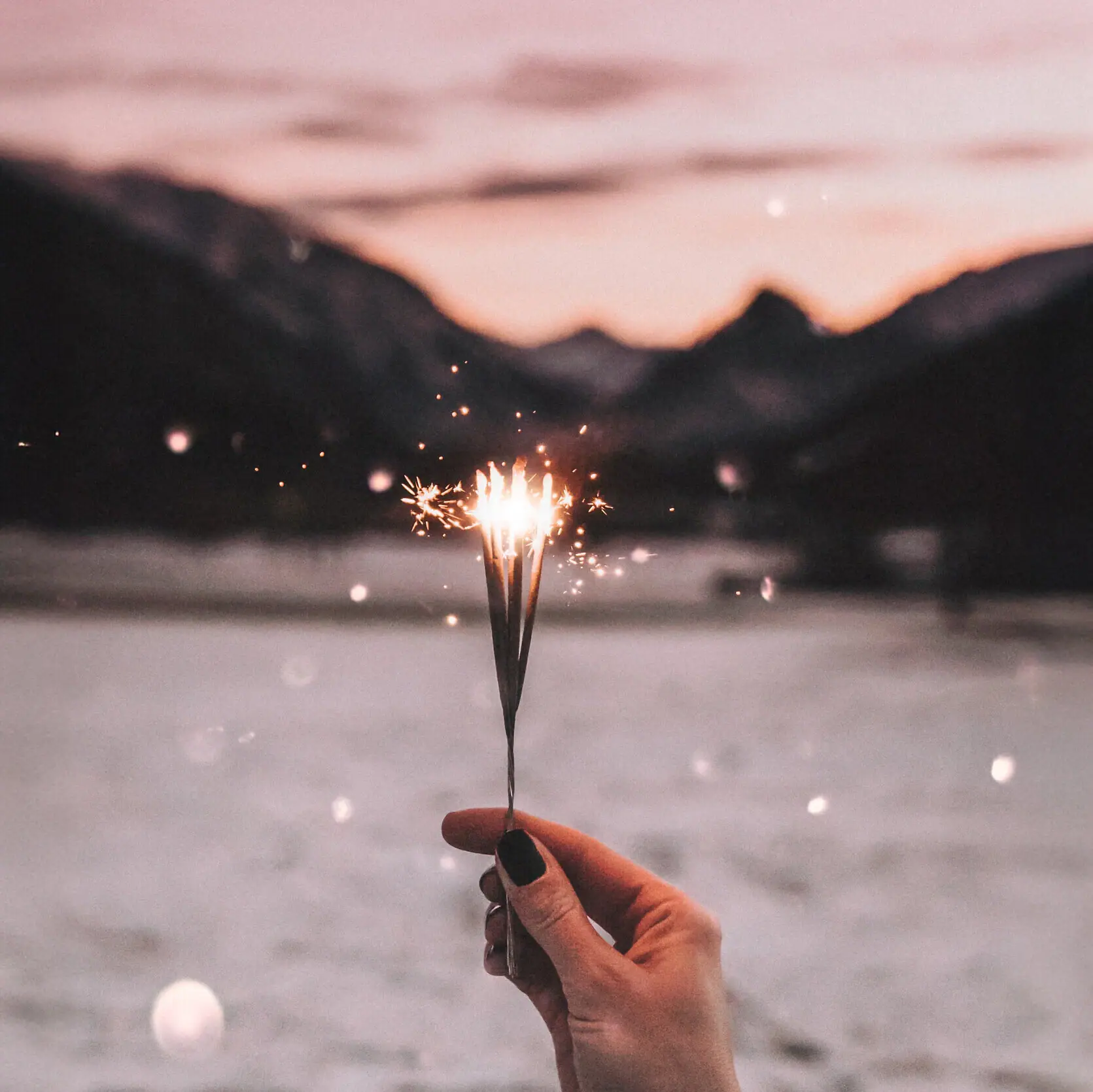 Hand hält Wunderkerze im Freien.