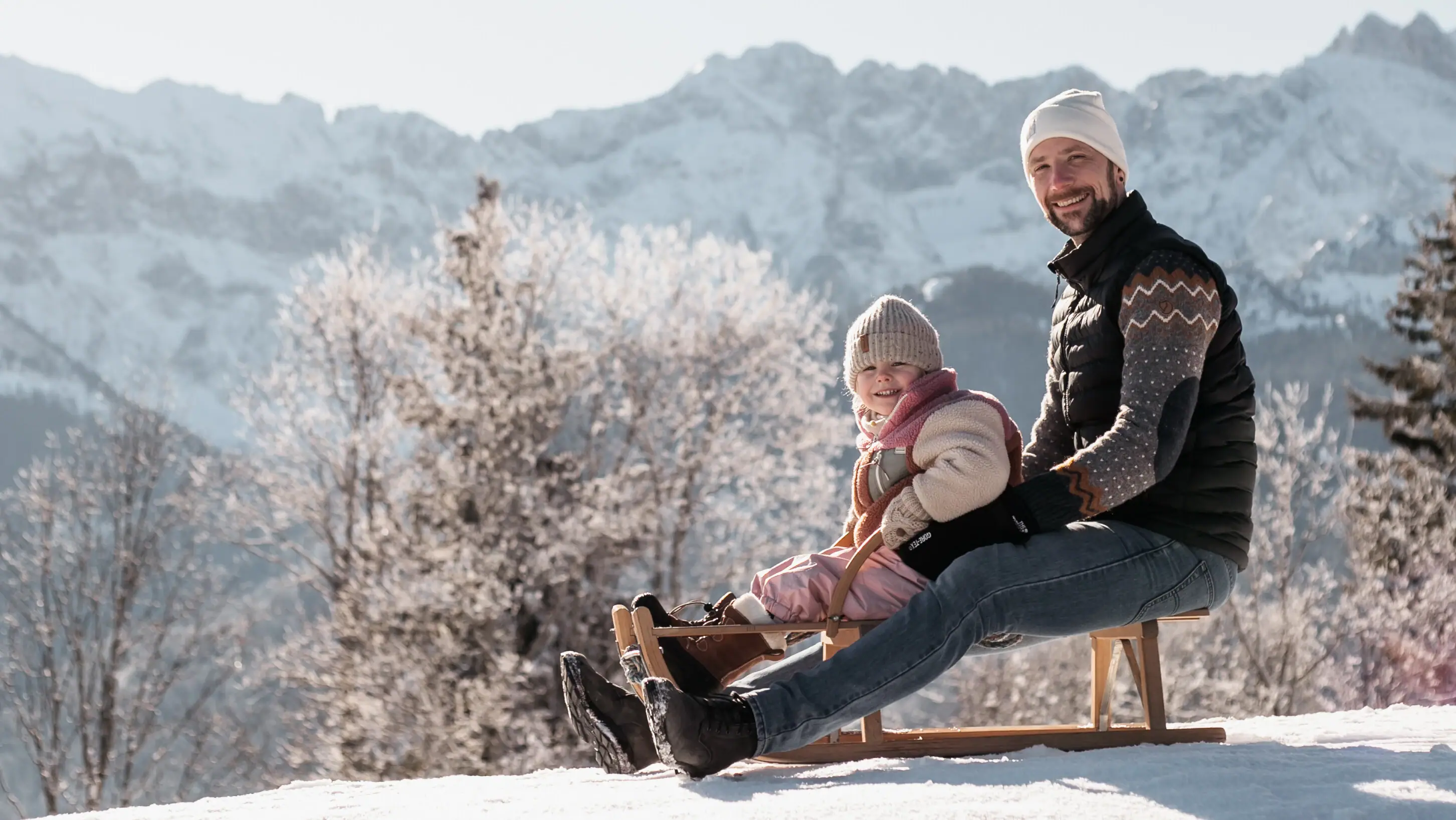 Ein Mann und ein Kind auf einem Schlitten im Schnee.