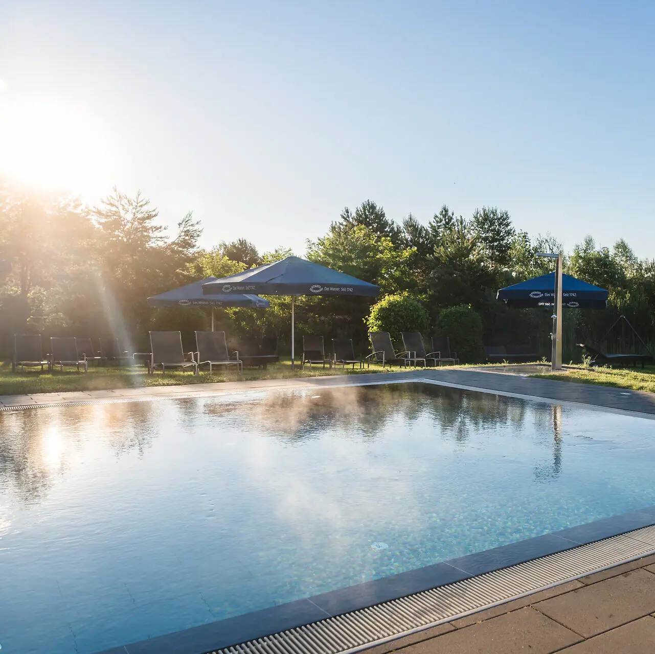 Ein Pool mit Sonnenschirmen und Gras.