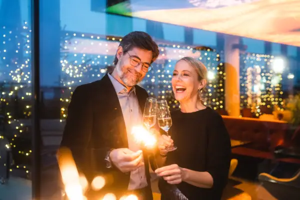 Silvester im aja Travemünde Ein Mann und eine Frau halten Sektgläser und Wunderkerzen