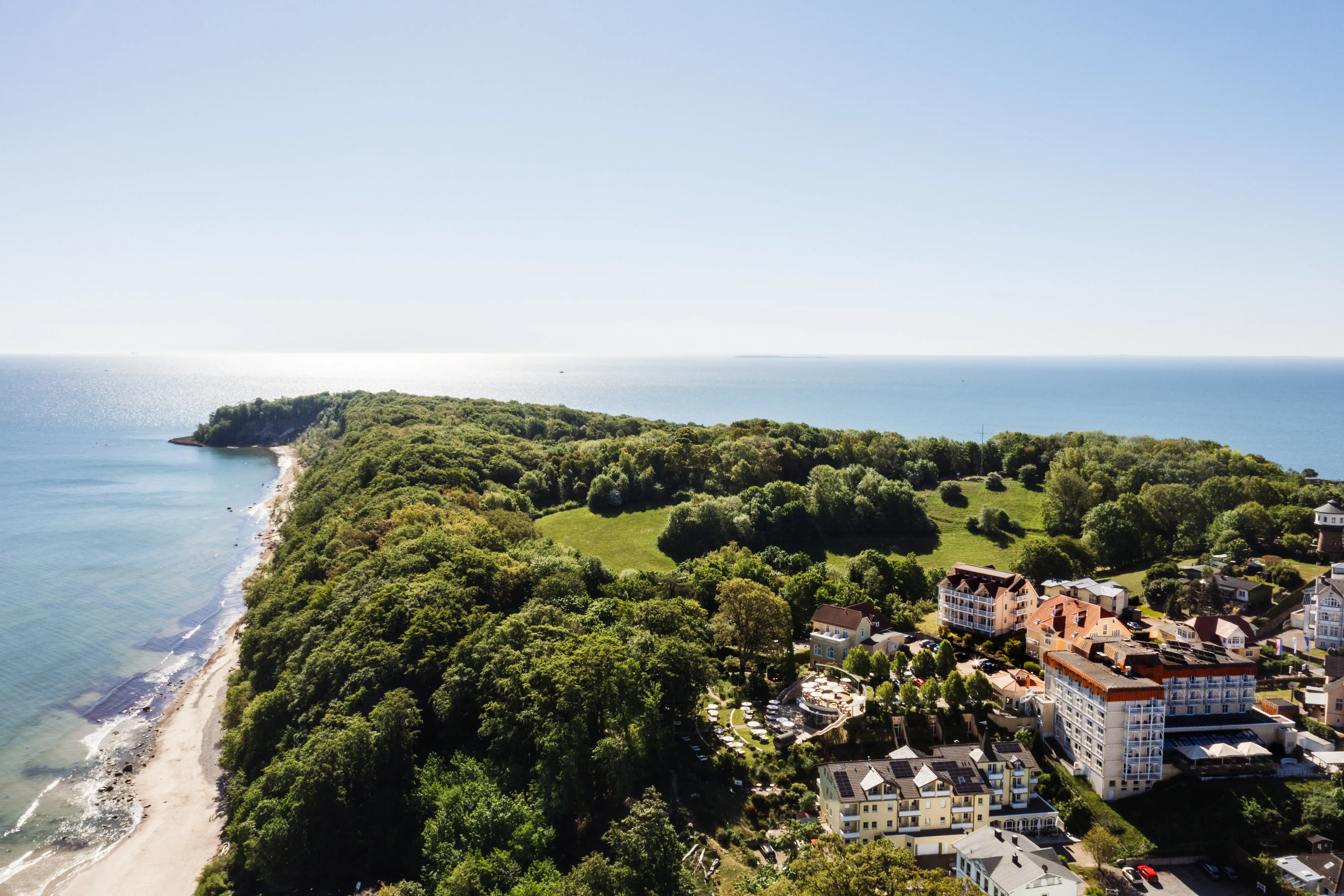 Nordperd Landschaft mit Bäumen und Gebäuden am Küstenstreifen, blauer Himmel im Hintergrund.