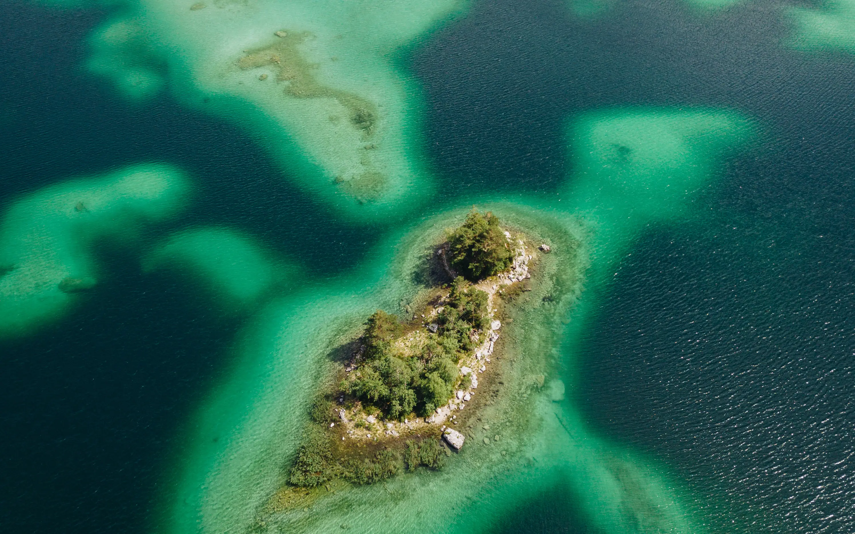 Luftaufnahme von Inseln im Eibsee umgeben von türkisfarbenem Wasser.