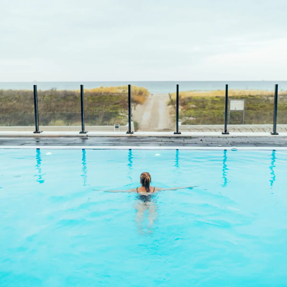 Außenpool im aja Warnemünde Frau schwimmt in einem Pool im Freien.