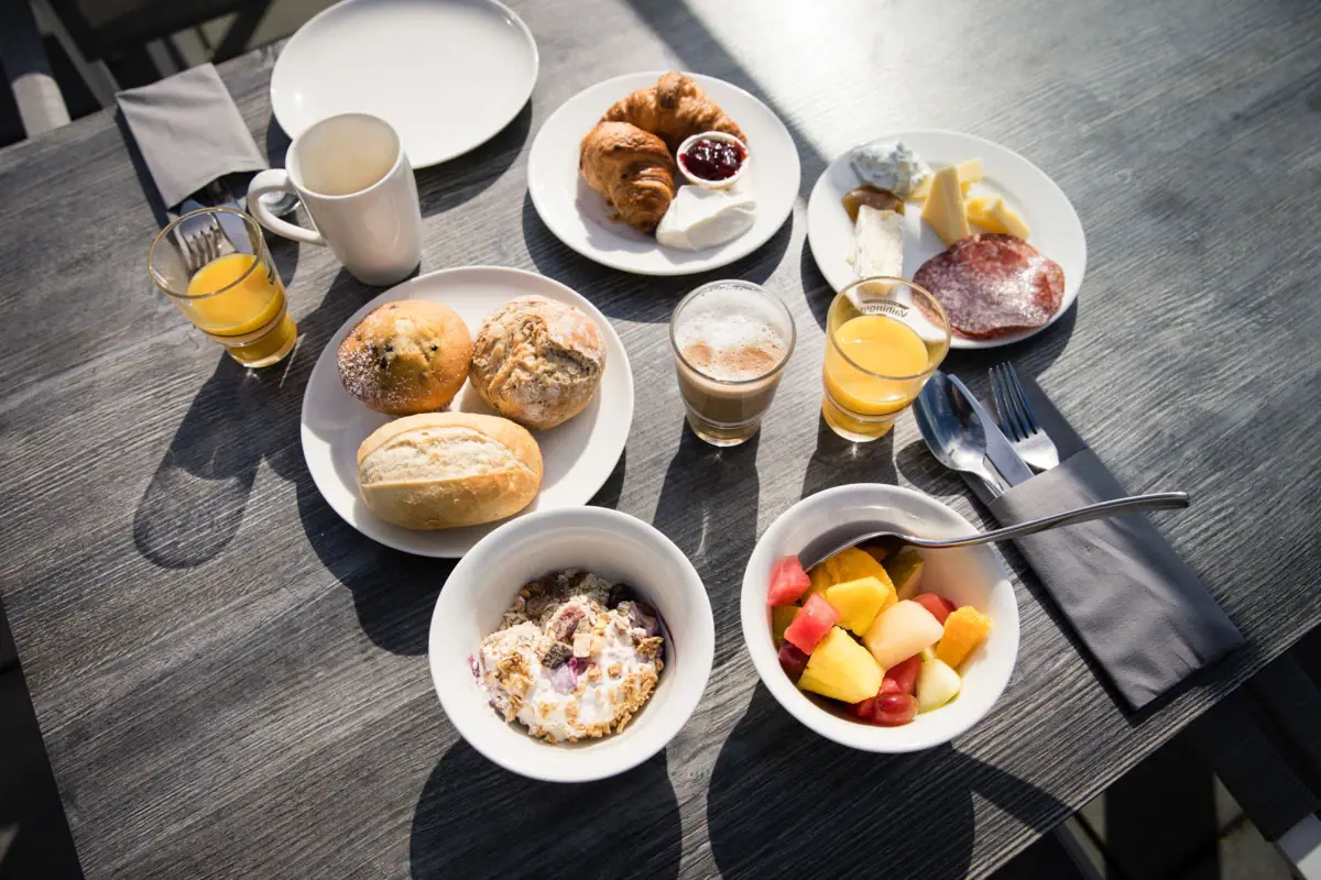 Frühstück im JEDERMANNS Ein Tisch mit Tellern voller Speisen und Getränken.