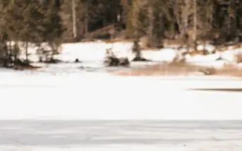 Eine Person sitzt auf einem Baumstamm im Schnee.