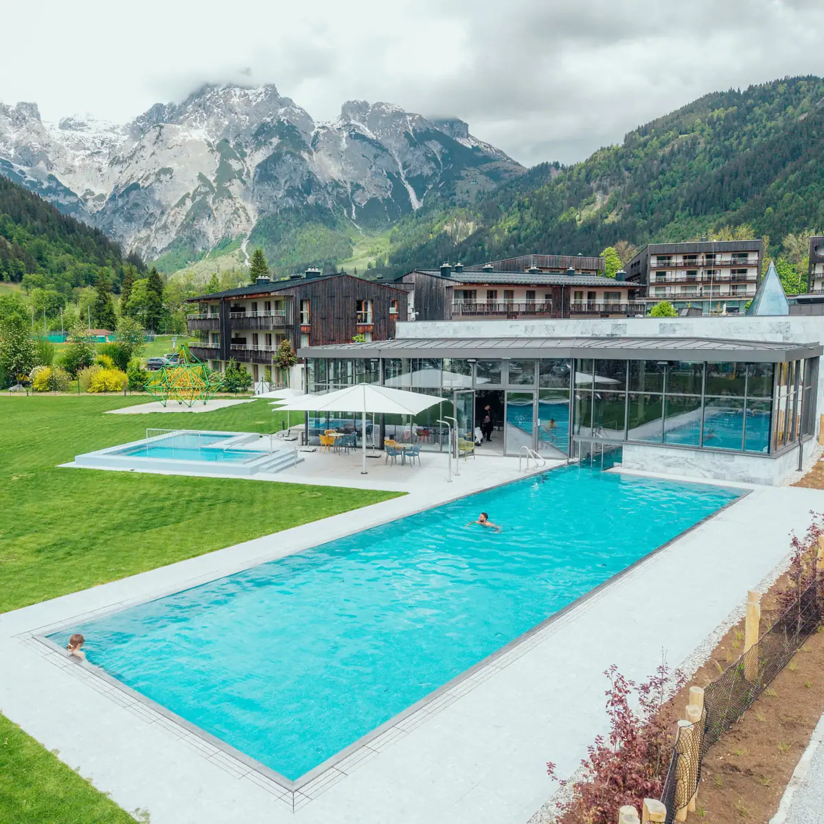 Schwimmbad mit einem Gebäude und Bergen im Hintergrund.