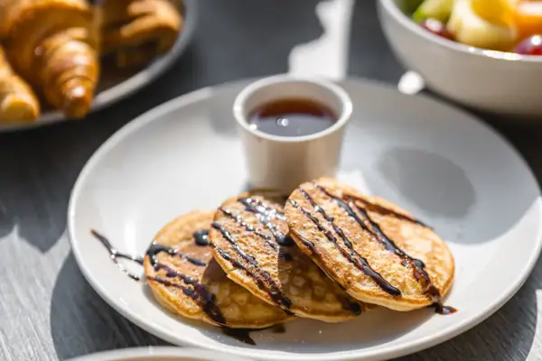 Ein Teller mit Pfannkuchen und Sirup sowie eine Tasse mit Sirup.
