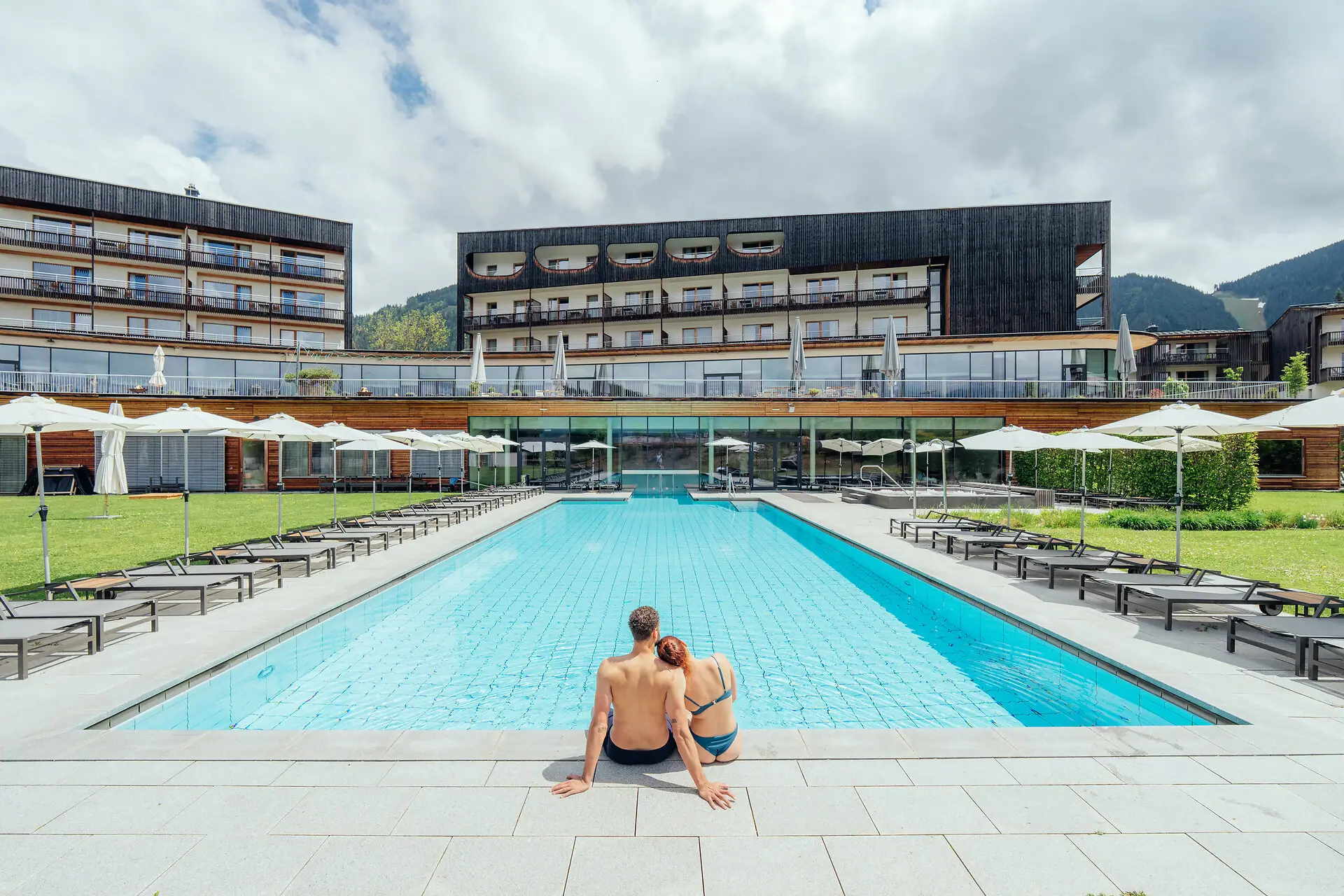 Ein Mann und eine Frau sitzen an einem Pool.