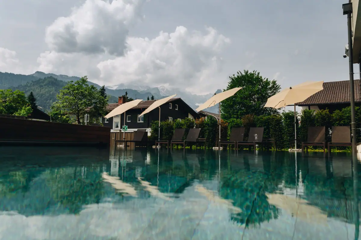 Ein Pool mit Stühlen und Sonnenschirmen vor Häusern.