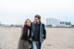 Ein Mann und eine Frau spazieren am Strand entlang.