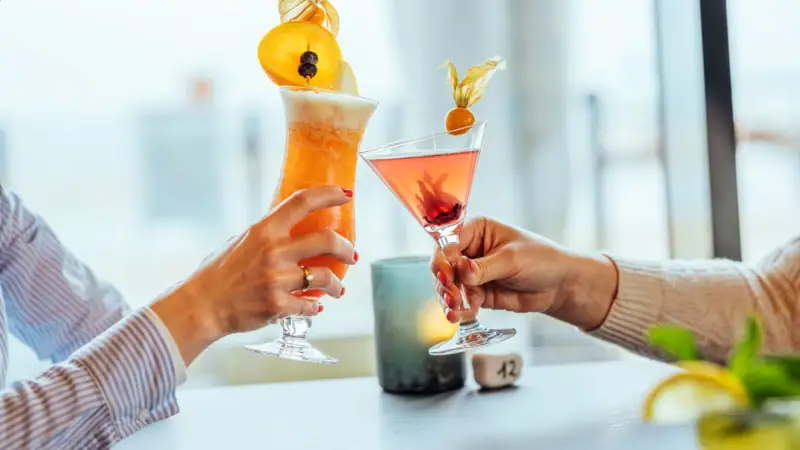 Cocktails Ein Paar Hände hält Gläser mit Getränken.