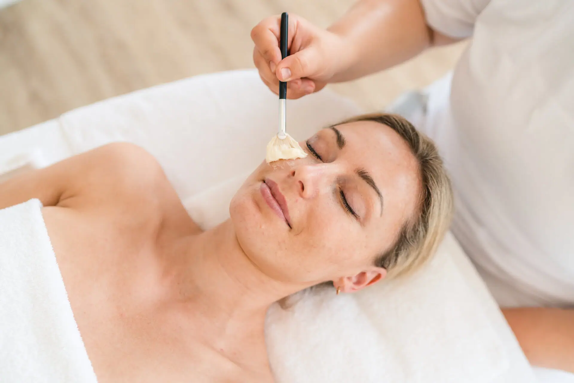 Kosmetik im aja Grömitz Eine Frau liegt mit einem Pinsel im Gesicht.