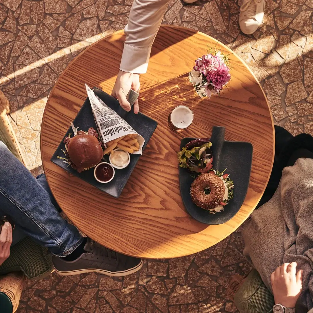 Person hält einen Teller mit Essen auf einem Tisch.