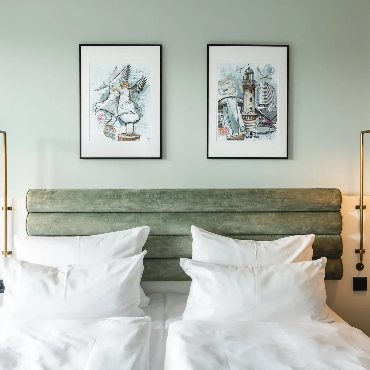 Zimmer im aja Warnemünde Bett mit weißen Kissen und grünem Kopfteil, flankiert von zwei Lampen.