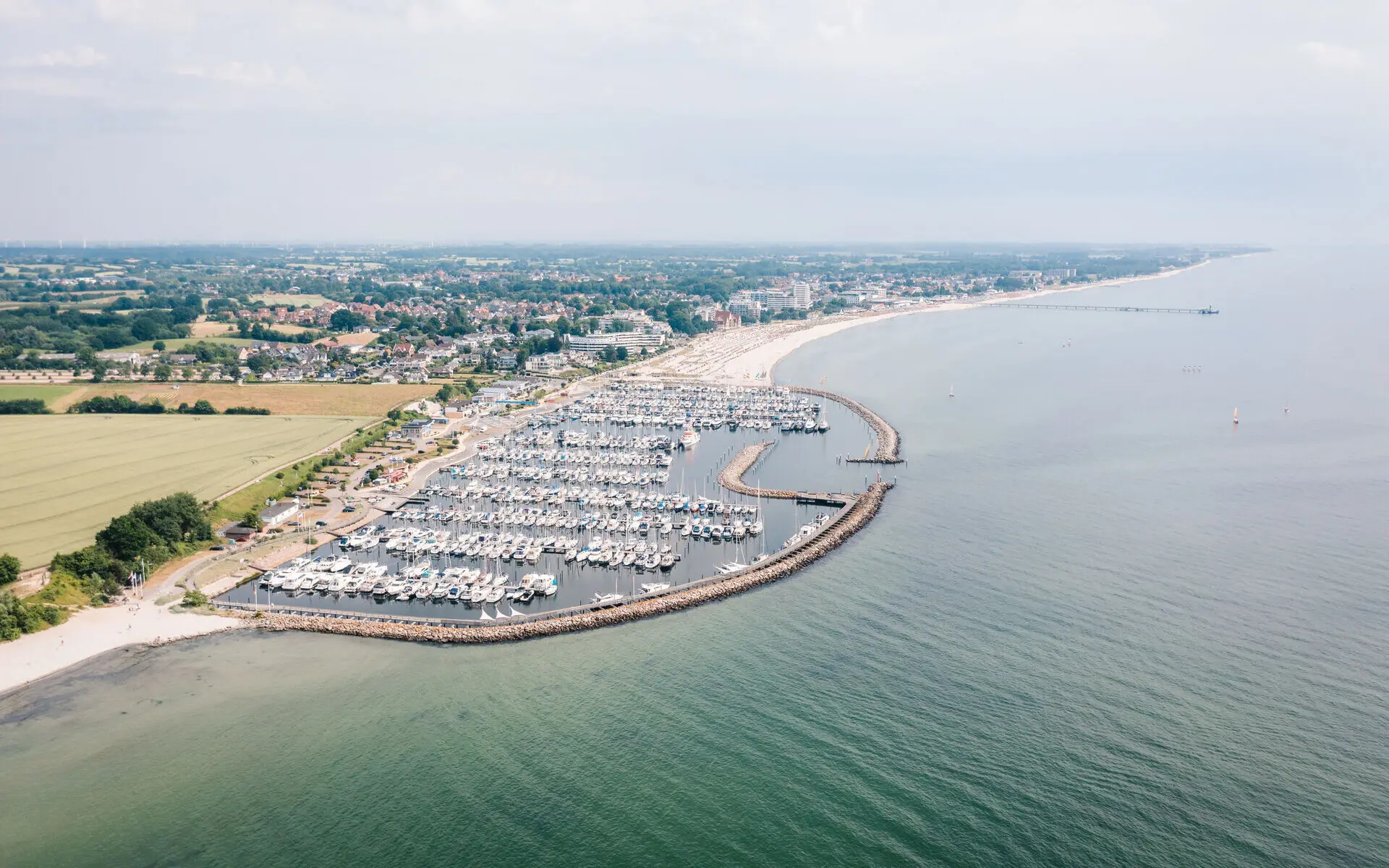 Marina mit Booten auf dem Wasser, umgeben von einer Küstenlandschaft.