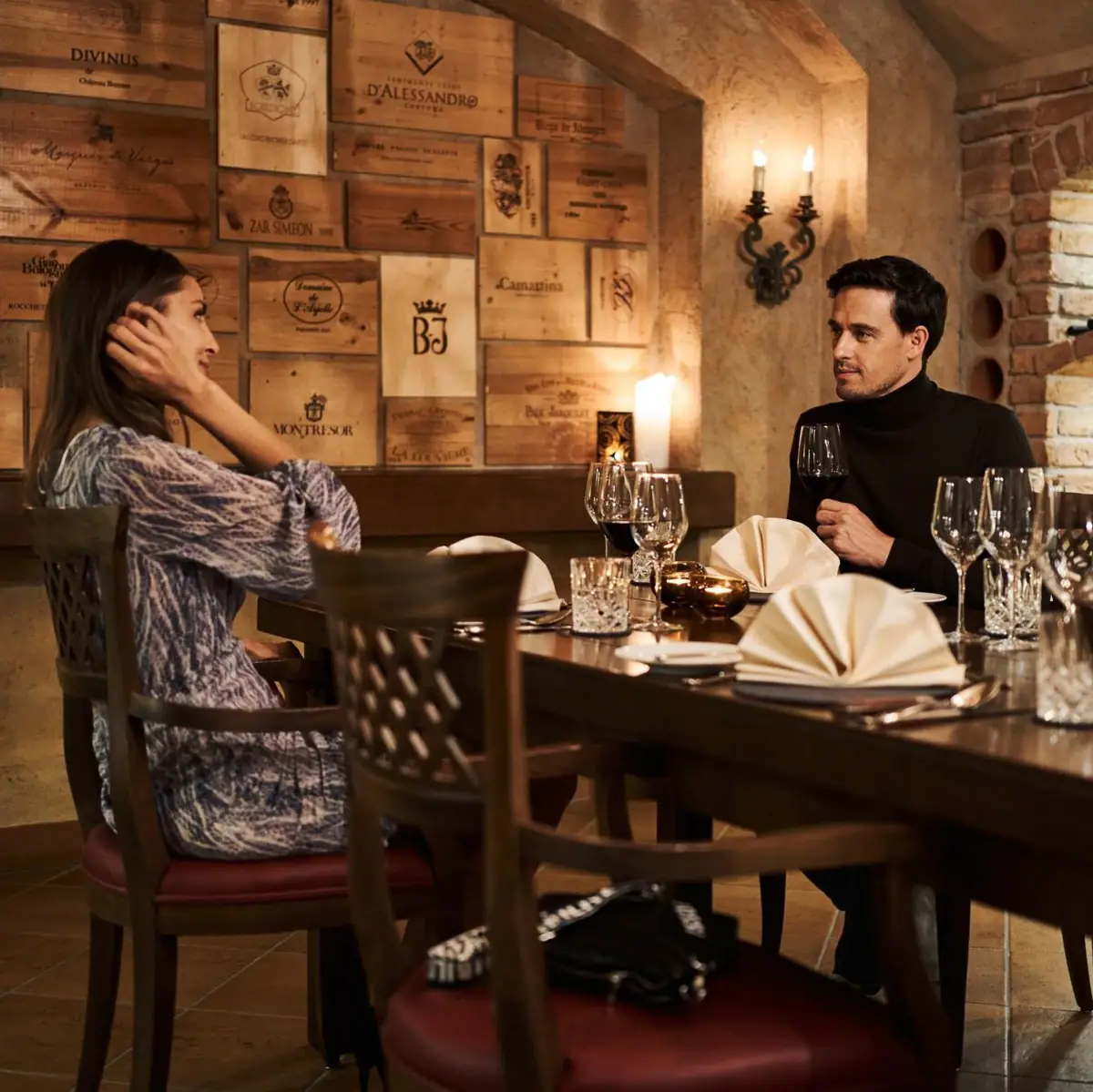 Dinner im Weinkeller Ein Mann und eine Frau sitzen an einem Tisch mit Weingläsern.