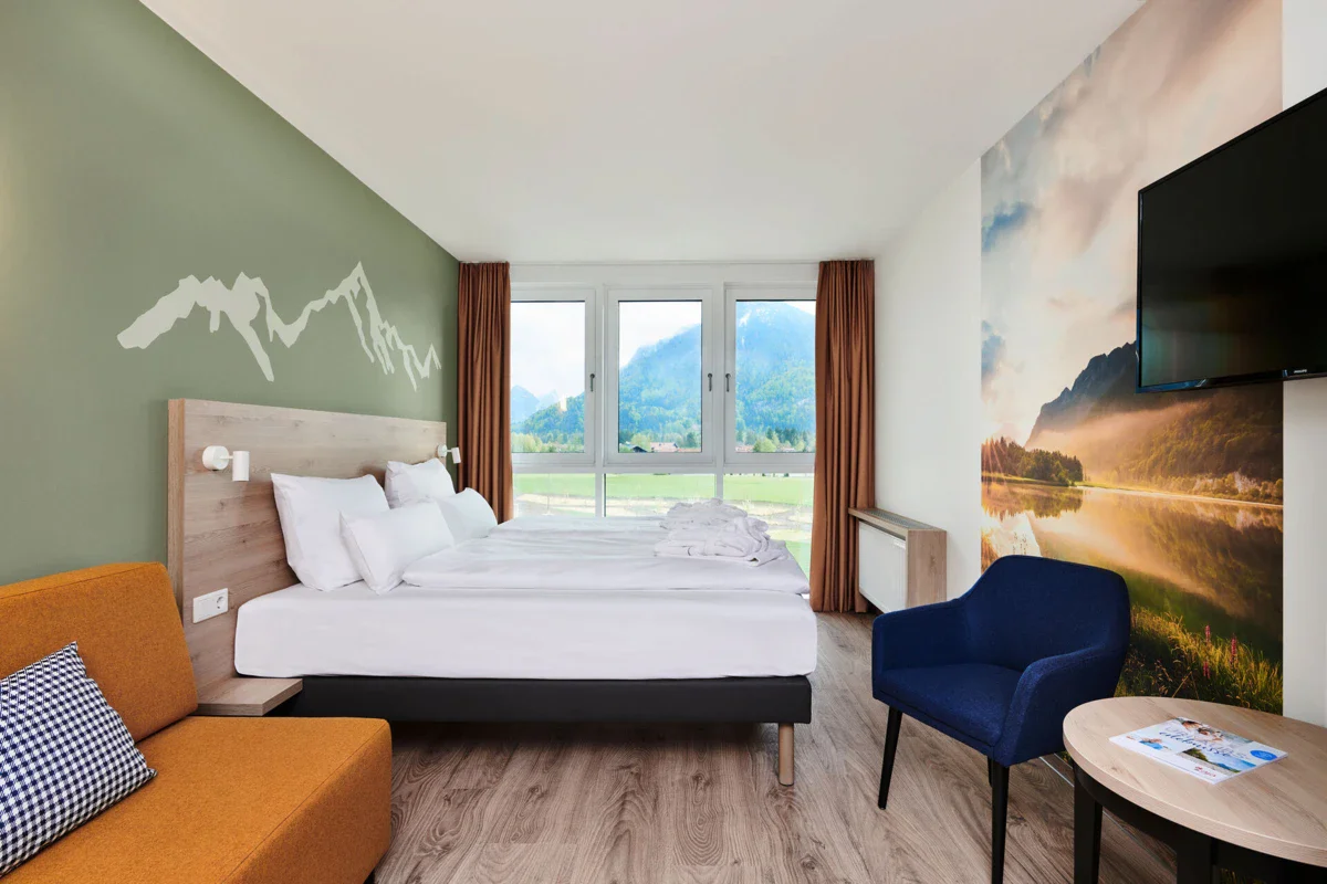 Ein Zimmer mit einem Bett und Stühlen im aja Hotel Ruhpolding.