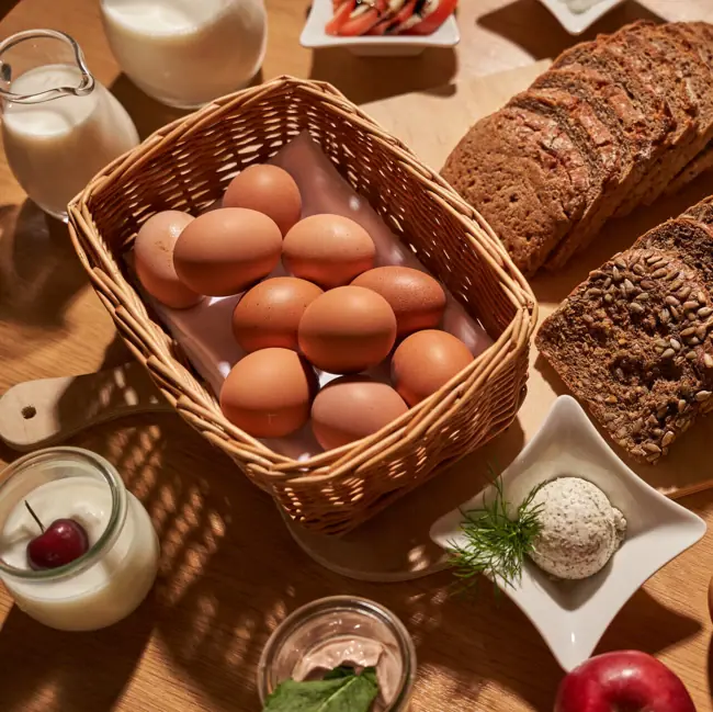 Lebensmittel Ein Korb mit Eiern und Brot auf einem Tisch.