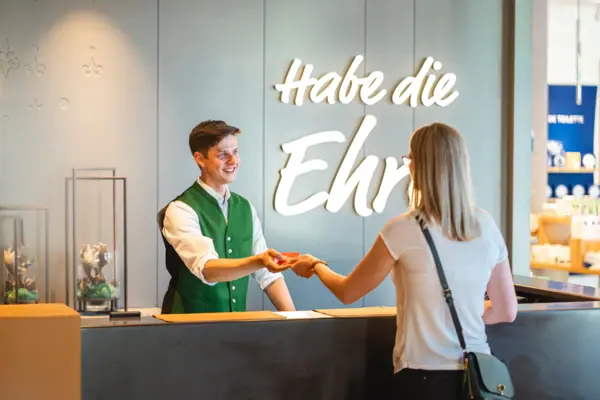 Ein Mann übergibt einer Frau an einem Empfangstresen die Zimmerkarte.