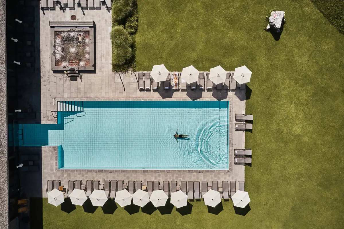 Schwimmbecken mit Sonnenschirmen und Rasen.