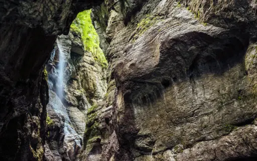 Wasserfall in der Partnachklamm, umgeben von Moos und Felswänden.