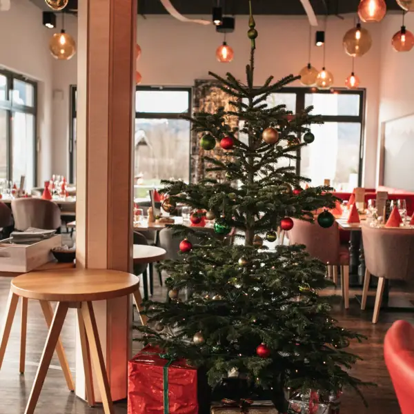 Ein Weihnachtsbaum in einem Raum mit Tischen und Stühlen.