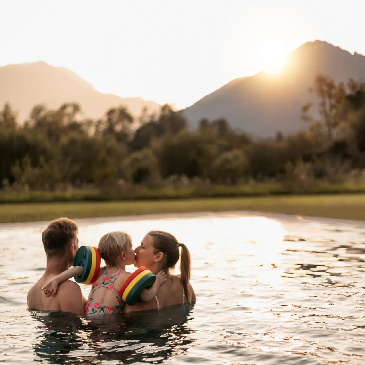 Eine Familie in einem Pool mit Bergen im Hintergrund.