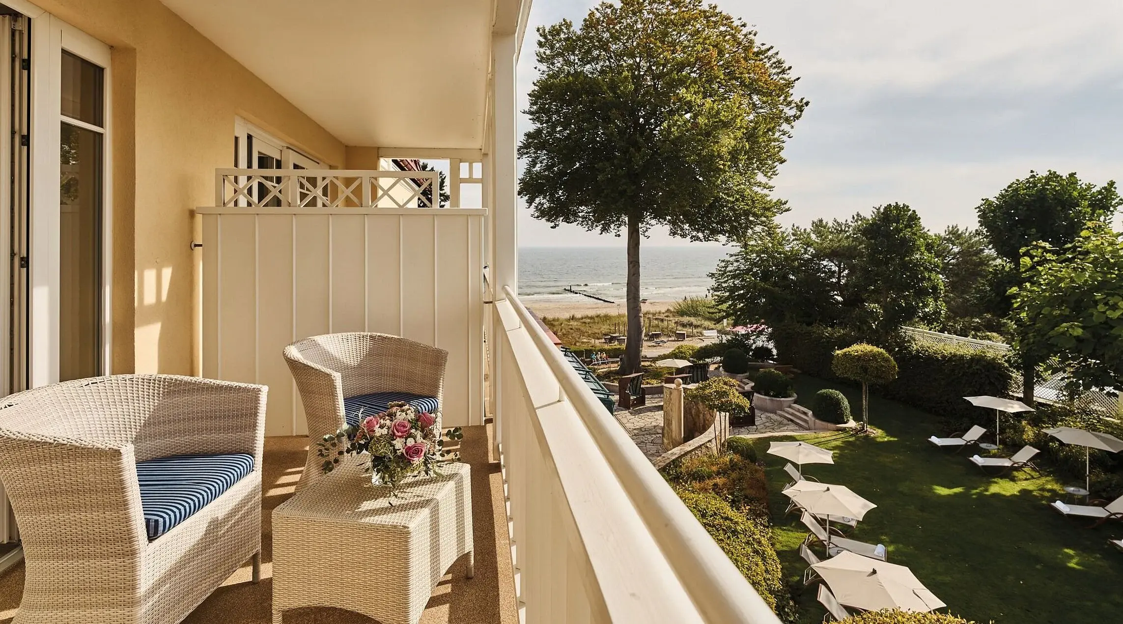 Ein Balkon mit Stühlen, einem Tisch und einem Baum vor einem Gebäude.