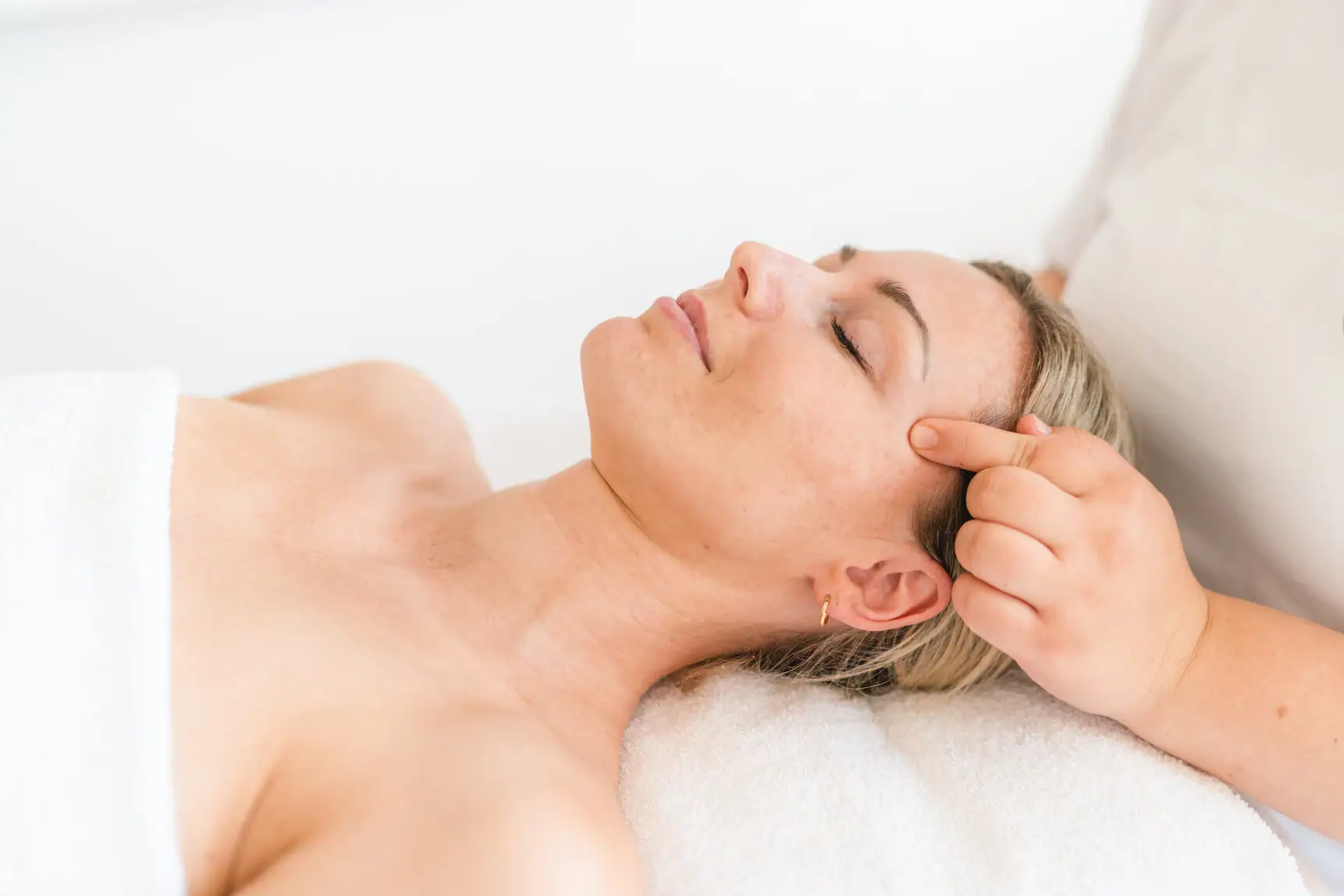 Anwendung im aja Grömitz Frau liegt auf einem Massagetisch.