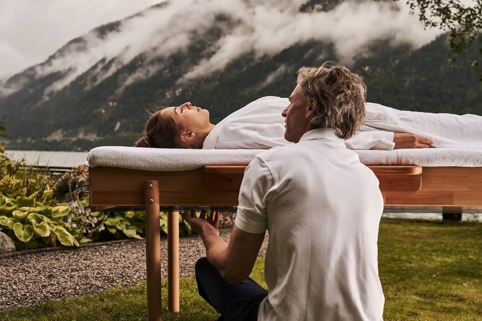 Massage Ein Mann kniet auf einem Tisch, auf dem eine Frau liegt.