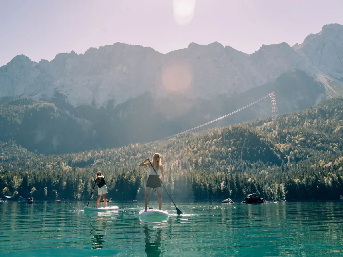 SUP Eibsee Frauen auf Paddleboards auf einem See mit Bergen im Hintergrund.