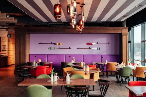 Ein Raum mit Tischen und Stühlen und einer lila Wand mit Rudern.