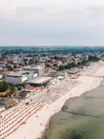 Luftaufnahme eines belebten Strandes mit vielen Menschen und Gebäuden.