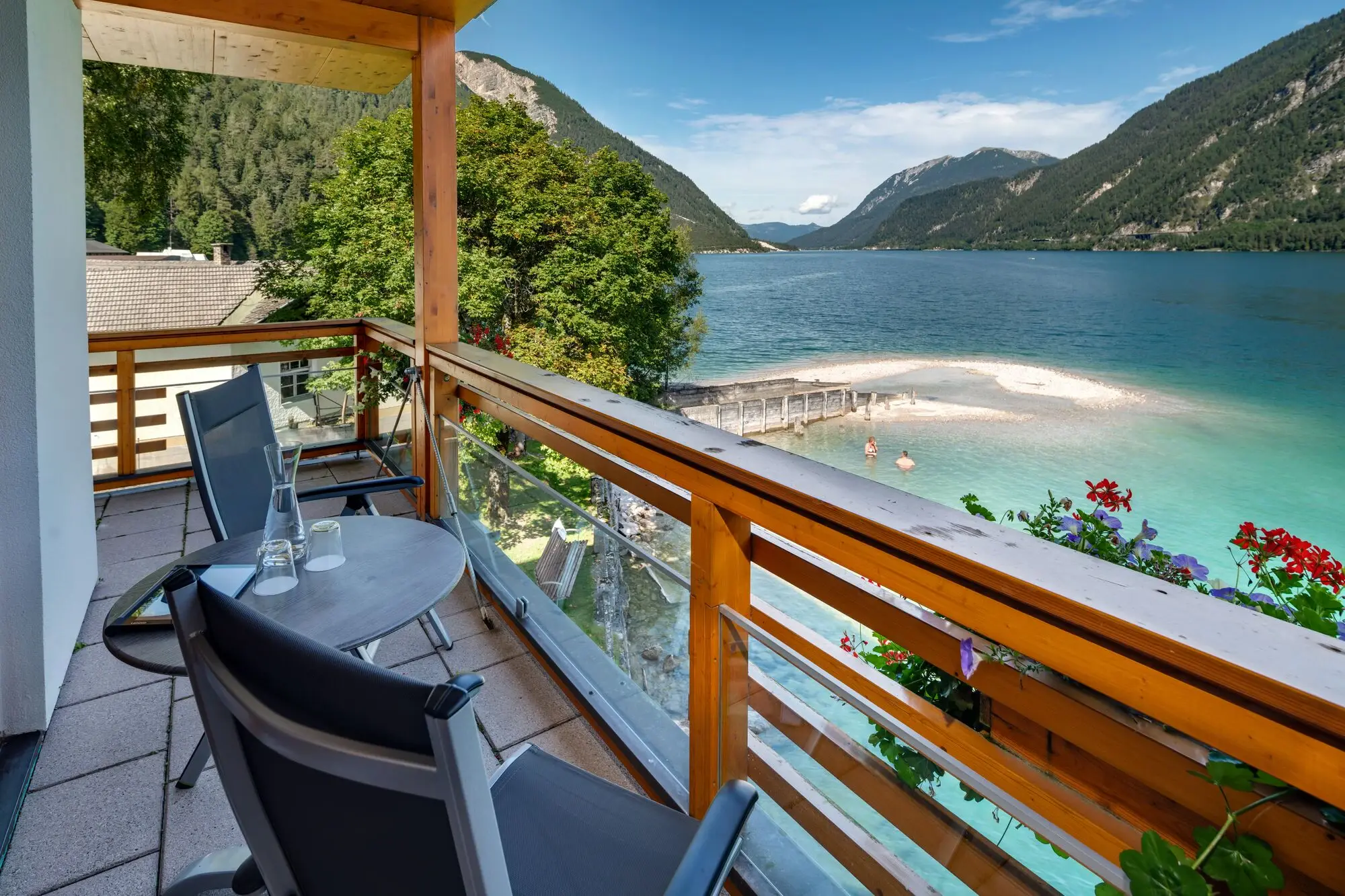 Ein Balkon mit Tisch und Stühlen, der auf ein Gewässer blickt.