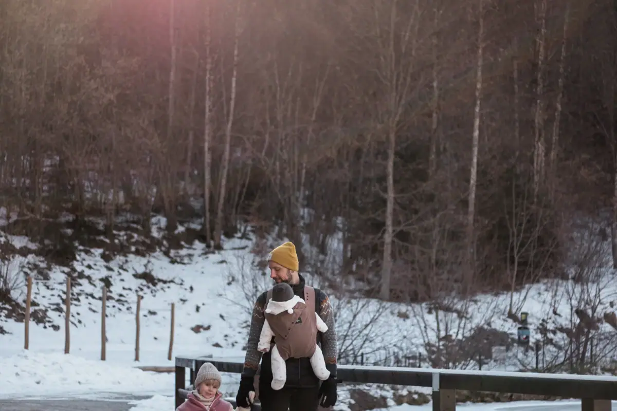 Ein Mann und ein Kind gehen im Schnee über eine Brücke.