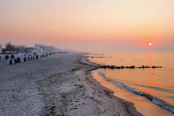 Strand Grömitz Strand mit Menschen bei ruhigem Wasser und klarem Himmel.