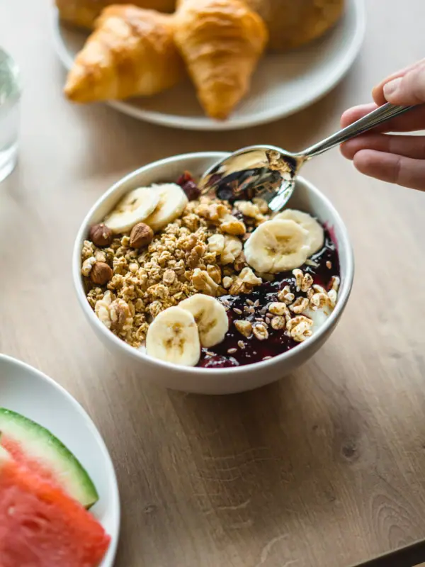 Eine Schüssel mit Granola, Obst und einem Löffel.