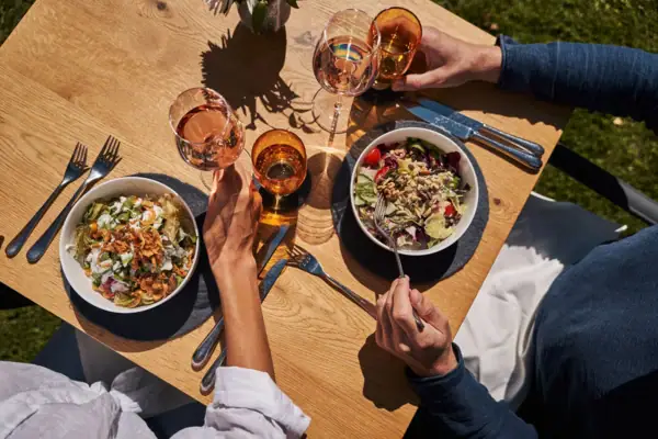 Eine Gruppe von Menschen isst an einem Tisch mit Essen und Getränken.