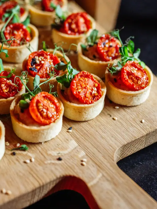 Kleine Tartelettes mit Tomaten auf einem Brett