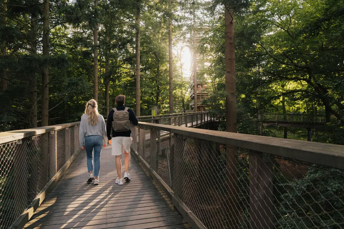 Ein Mann und eine Frau gehen auf einer Brücke beim Baumwipfelpfad in Usedom