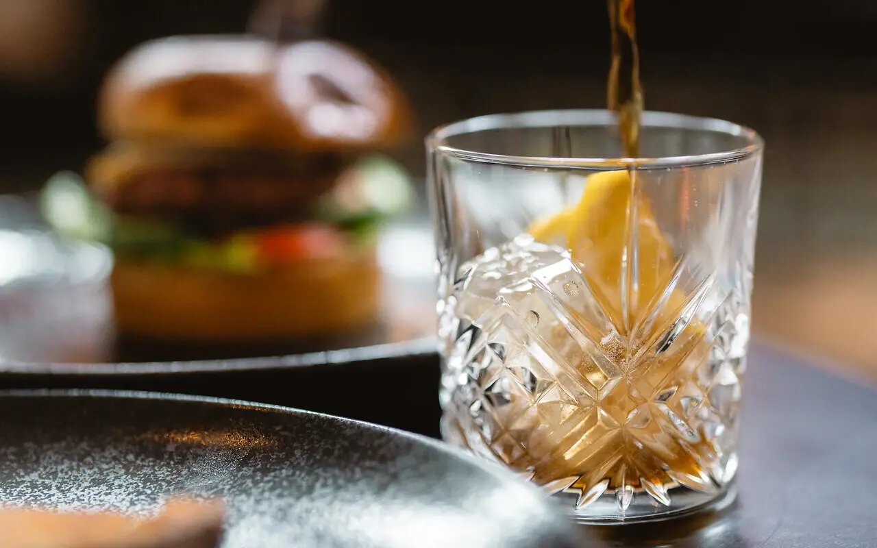 Drink Eine Person schenkt ein Getränk in ein Glas ein.