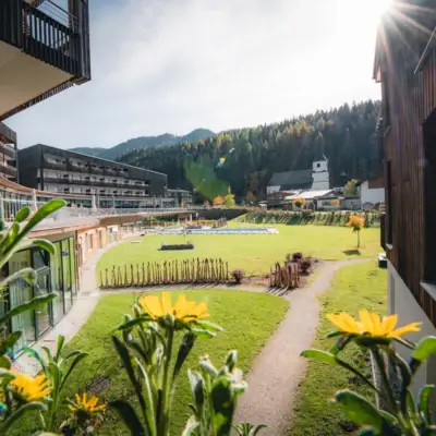 Grasfläche mit Gebäuden und Bäumen im Hintergrund