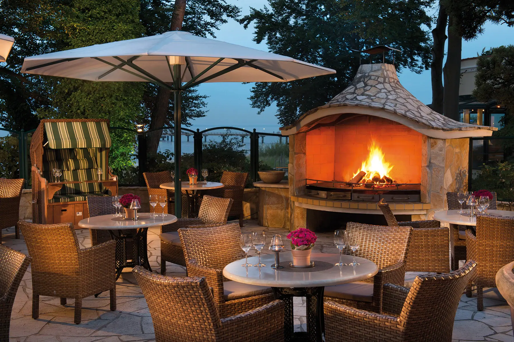 Ein Tisch und Stühle um eine Feuerstelle auf einer Terrasse.