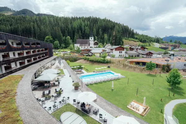 Ein Gebäude mit einem Pool im Vordergrund und Bäumen im Hintergrund.