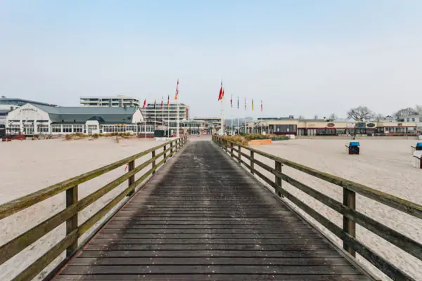 Holzbrücke über einem Strand mit klarem Himmel im Hintergrund.