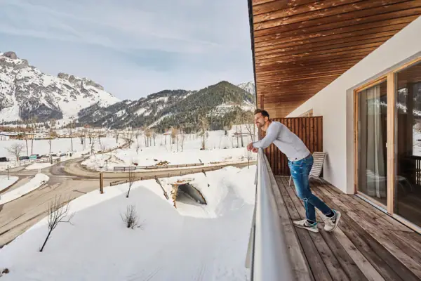 Ein Mann steht auf einem Balkon im Schnee.
