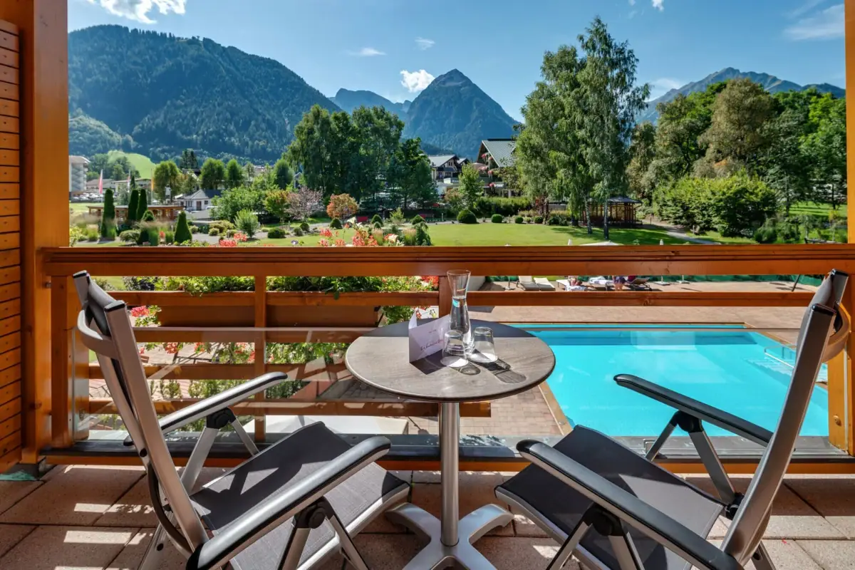 Ausblick vom Balkon Ein Tisch und Stühle auf einem Balkon mit Blick auf einen Pool.