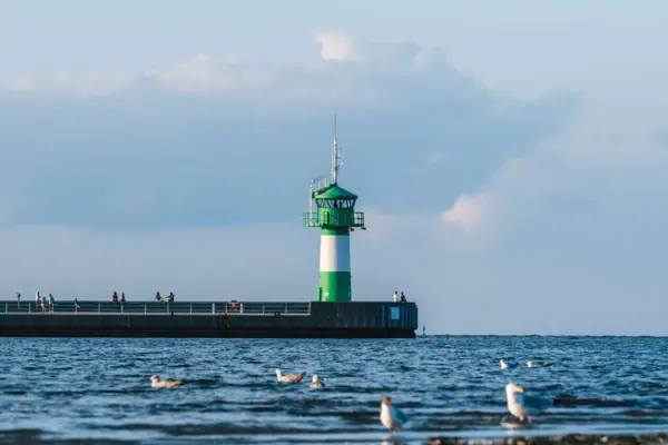Ein Leuchtturm auf einem Pier vor bewölktem Himmel.