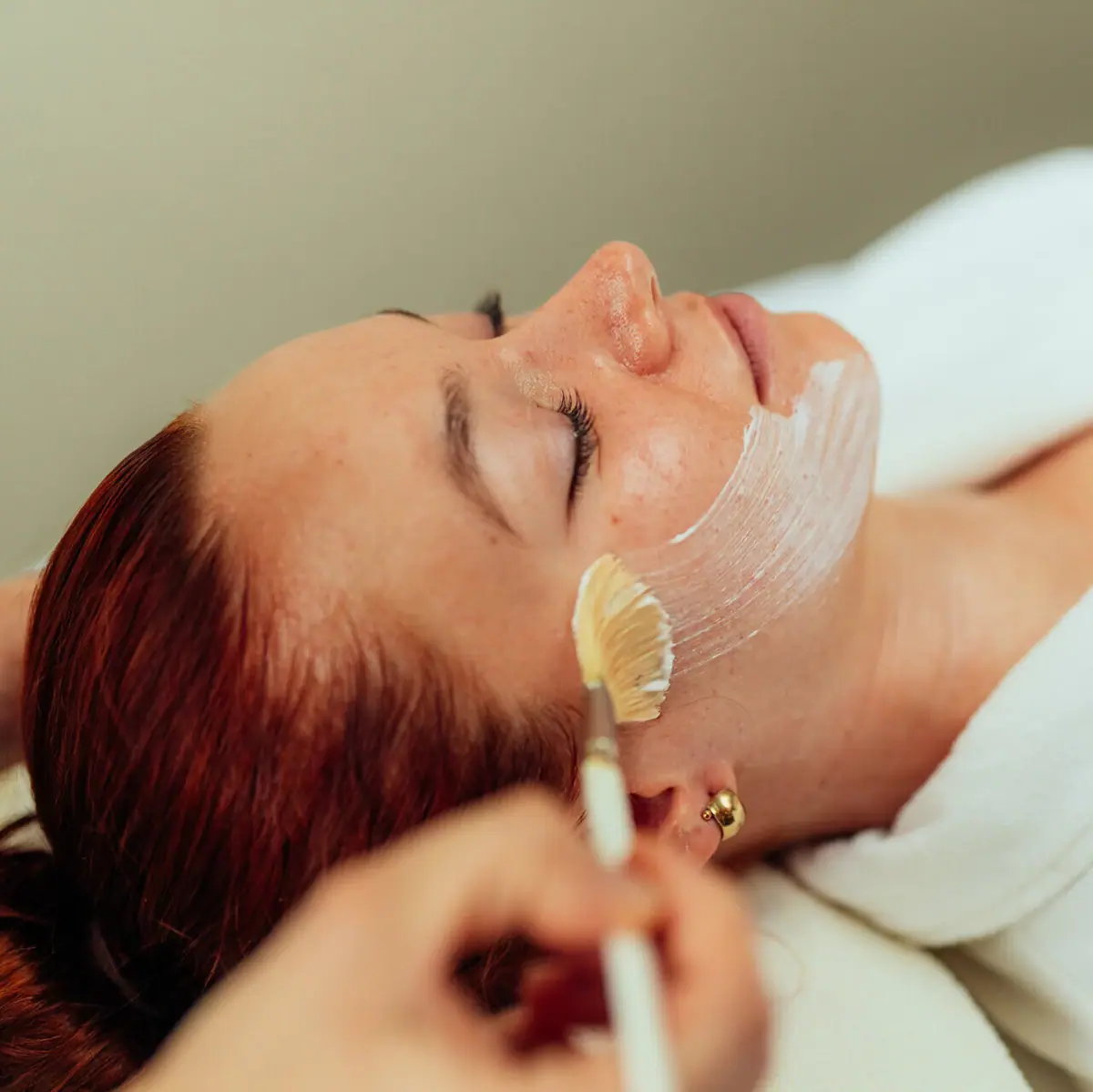 Kosmetik Eine Frau liegt mit einer weißen Maske im Gesicht.